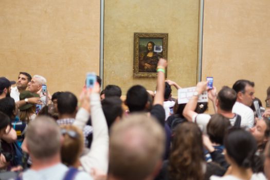 Paris, France - June 12: Crowd of visitors takes photos of Leonardo DaVinci's Mona Lisa, one of world's most famous work of art, at Louvre Museum on 12th of June ,2016 in Paris, France.