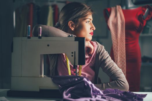 Beautiful tired woman sits in front of the sewing machine and thinking. Vintage concept.