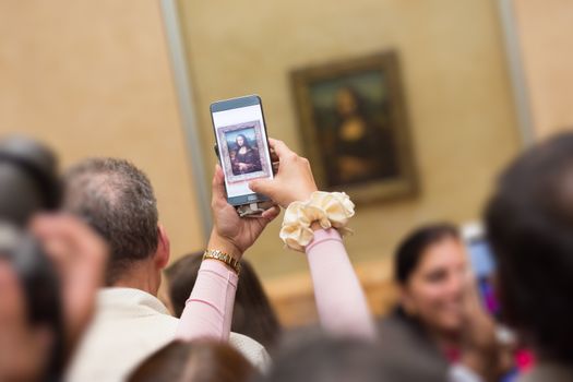 Crowd of visitors takes photos of Leonardo DaVinci's Mona Lisa, one of world's most famous work of art, at Louvre Museum in Paris, France.