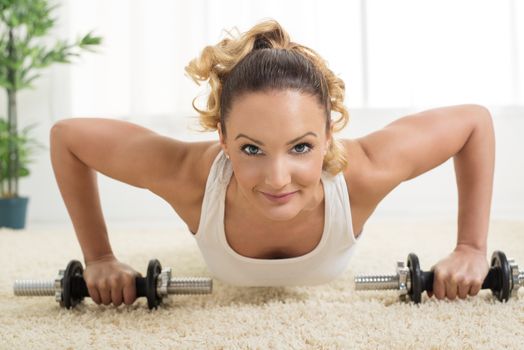 Beautiful young woman doing push-up at home. Looking at camera. Close-up.