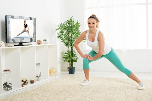 Beautiful young woman stretching out her legs at home in front of the tv