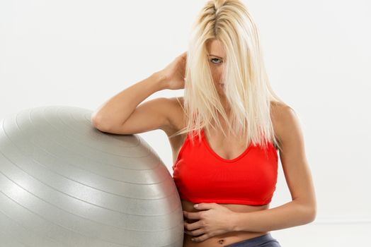 Beautiful smilling blond woman resting after workout. Looking at camera. White background.