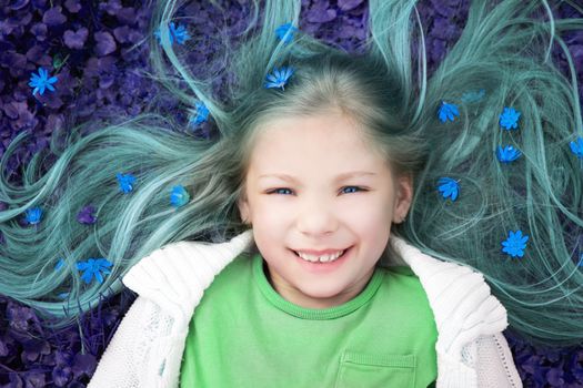 Abstract colorized of beautiful smiling little girl lying on the flower meadow in spring and looking at camera.