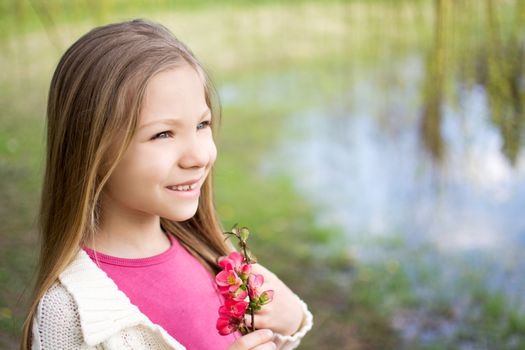 Smiling cute little girl holding sprin flower in the park and thinking.