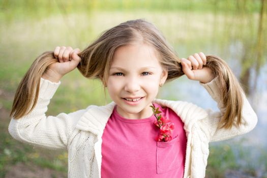 Beautiful funy little girl in the park in spring.
