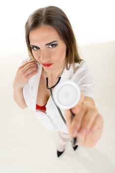 Beautiful smiling sexy nurse standing with stethoscope on white background. Looking at camera.