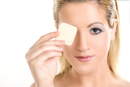 Beautiful woman holding make up sponge on her eye and looking at camera. White background.