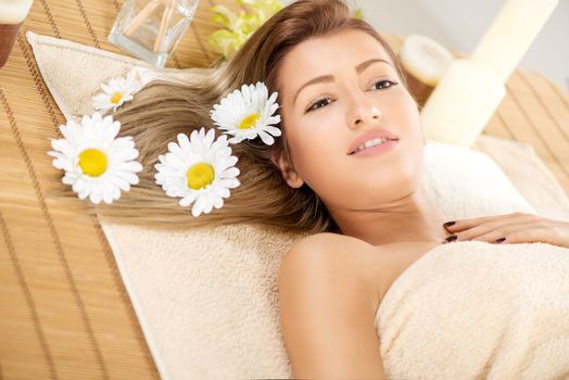Cute young woman lying on a towel during a skin care treatment at a spa. 
