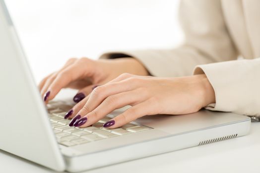 Close-up of female hand with painted nails on the keyboard of the laptop.