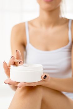 Close-up of moisturizing body cream in the hands of a young woman, unrecognizable face with a underwear. Selective focus.