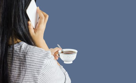 Isolated focused at hot drink in hand of women, girl back or rare view with mobile phone, women hold cup of coffee and talking on mobile or smartphone on plain background