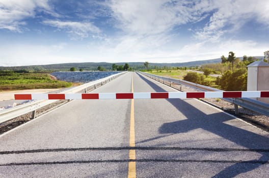 Red barricade at stop area ,barrier or blackade with long road o street way and  cloudy sky background