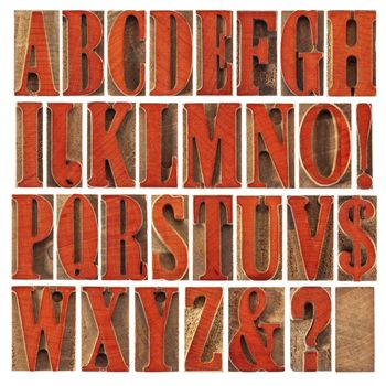 alphabet in modern letterpress wood type printing blocks stained by red ink,  a collage of 26 isolated letters, question mark, exclamation point, ampersand and dollar sign
