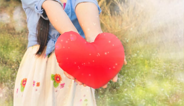 Girl hand give or present red heart in dreamy light with love, respect and care, women hold big red heart in wonderful glitter bokeh shining