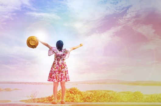 Colourful dreamy fancy mood of back or rare view girl or women standing and raising arms up high to sky embrace world freely with lens flare light on reservoir or lake background