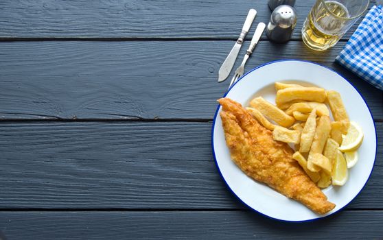 Fish and chips on a wooden table with space