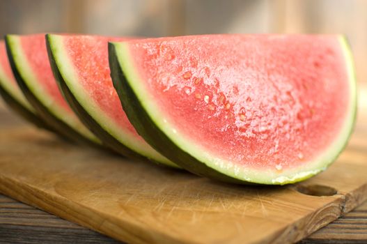 Watermelon slices close up on top of a wooden board 