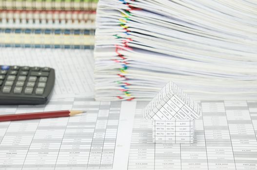 House on finance account have blur pencil with calculator and pile paperwork of report with colorful paperclip with stack notebook as background.