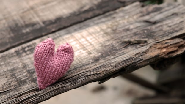 Lonely heart on wooden background, symbol of love with pink knitted heart in vintage color