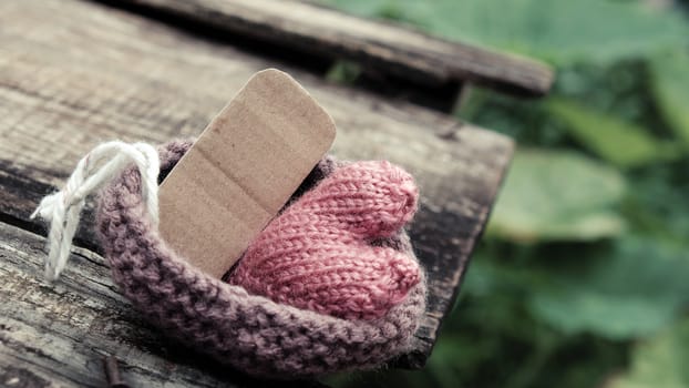 Lonely heart on wooden background, symbol of love with pink knitted heart in vintage color