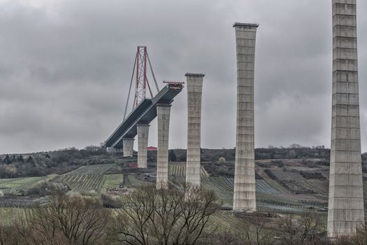 Bridge construction site under a dramatic sky. High Moselle Bridge under construction between Ürzig and Zeltingen - Rachtig seen from below.
