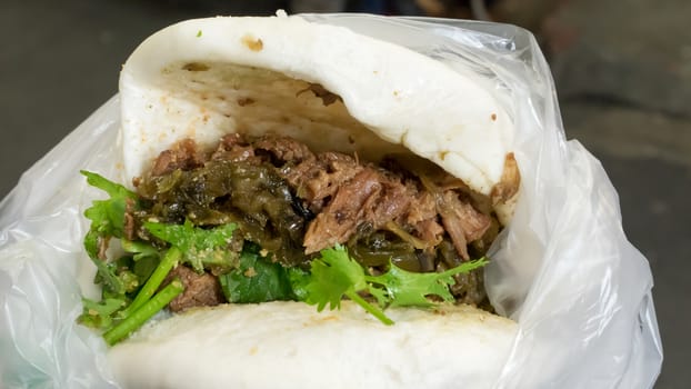 The close up of Taiwanese Pork Steamed Sandwich bun (gua bao) at food street market in Taipei, Taiwan.