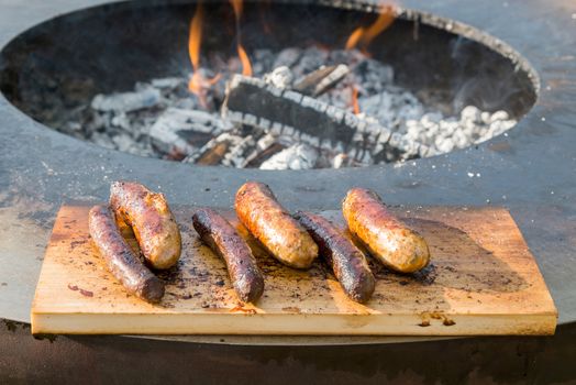 Grilling sausages on cutting board and barbecue grill