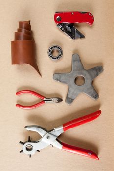 Working tools for embossed leather on brown background top view