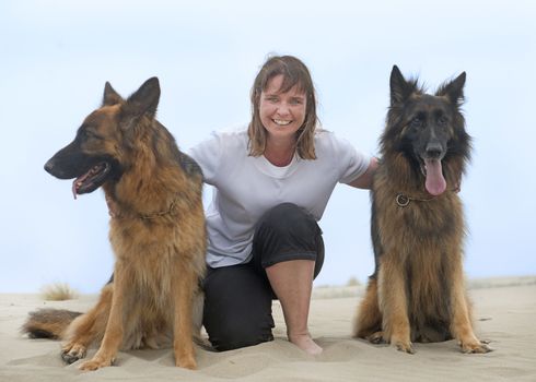 young woman and her two german shepherd on the beach