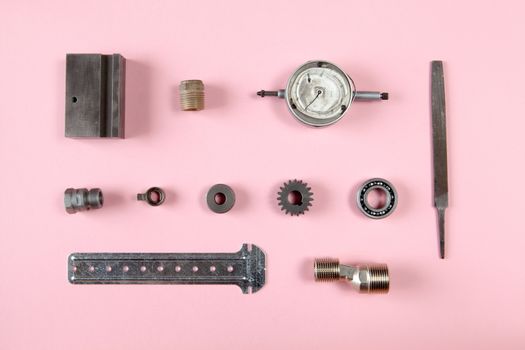 Mixture of different pieces of tools and machinery on pink background