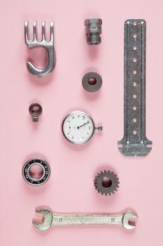 Mixture of different pieces of tools and machinery on pink background