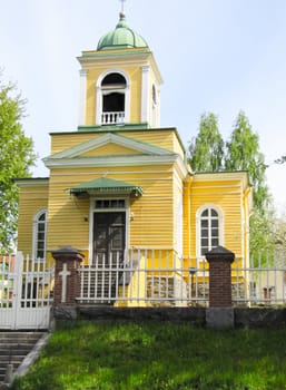 wooden Church in yellow on a blue sky background