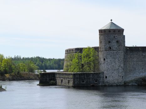 old castle by the river on a background of forest and blue sky