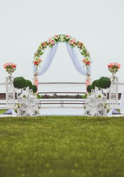 Wedding ceremony by the river. Arch decorated with flowers in the center of the composition