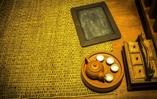 Wooden black board and teapot with cup on the bamboo mat