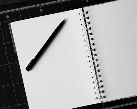 Blank notebook with pen on the table. black and white image.