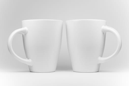Two white mugs in a mirrored arrangement in high-key
