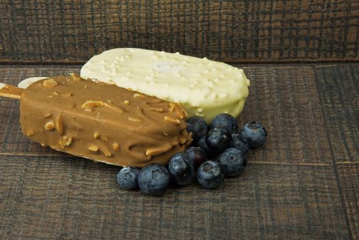 Two Ice cream on a stick , with cranberries on wooden ,vintage background. Horizontal view.