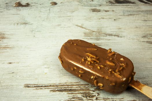 Chocolate ice lolly on a light wooden countertop in vintage style. Flat , horizontal view.