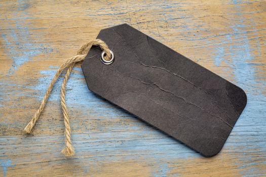black blank paper price tag with a twine against a grunge wood
