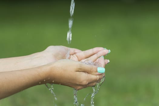 Clean water flows from the fingers of a young girl