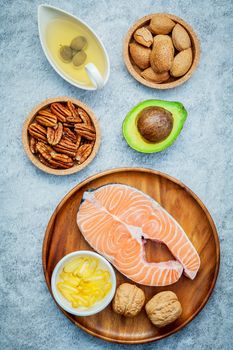 Selection food sources of omega 3 and unsaturated fats. Super food high omega 3 and unsaturated fats for healthy food. Almond ,pecan ,hazelnuts,walnuts ,olive oil ,fish oil ,salmon and avocado on stone background .