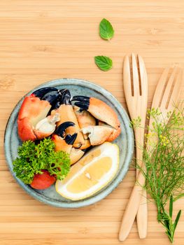 Fresh steamed red crabs leg in bowl . Red crabs leg with ingredients. Steamed red crabs leg with herbs Fennel ,parsley,rosemary,lemon and mint with fork on wooded cutting board.