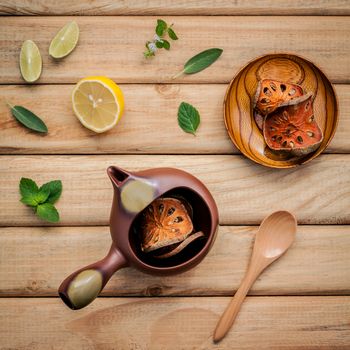 Herbal tea pot with fresh herbs sage ,peppermint ,dried indian bael, honey, lime and lemon on rustic wooden background.