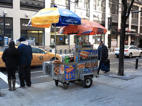A Manhattan hot dog stand with umbrellas.