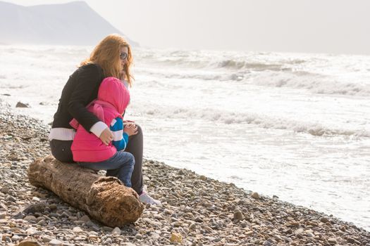 My mother and five year old daughter sitting on the beach, my mother hugged her frozen girl