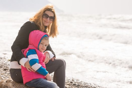 My mother and five year old daughter sit on the beach and looked at turning frame