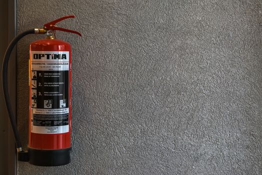 Red fire extinguisher hanging on the wall inside a shopping complex in the city of Lappeenranta, Finland.