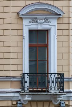 A window with an arch and balcony on the facade of the beige building. From the series window of Saint-Petersburg.