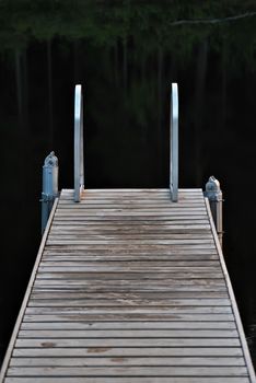 Small bridge for bathing in a forest lake a cool summer evening.